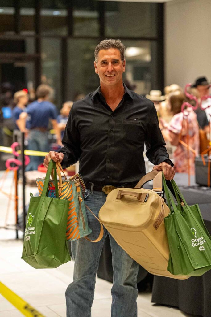 Man holding multiple shopping bags at event.
